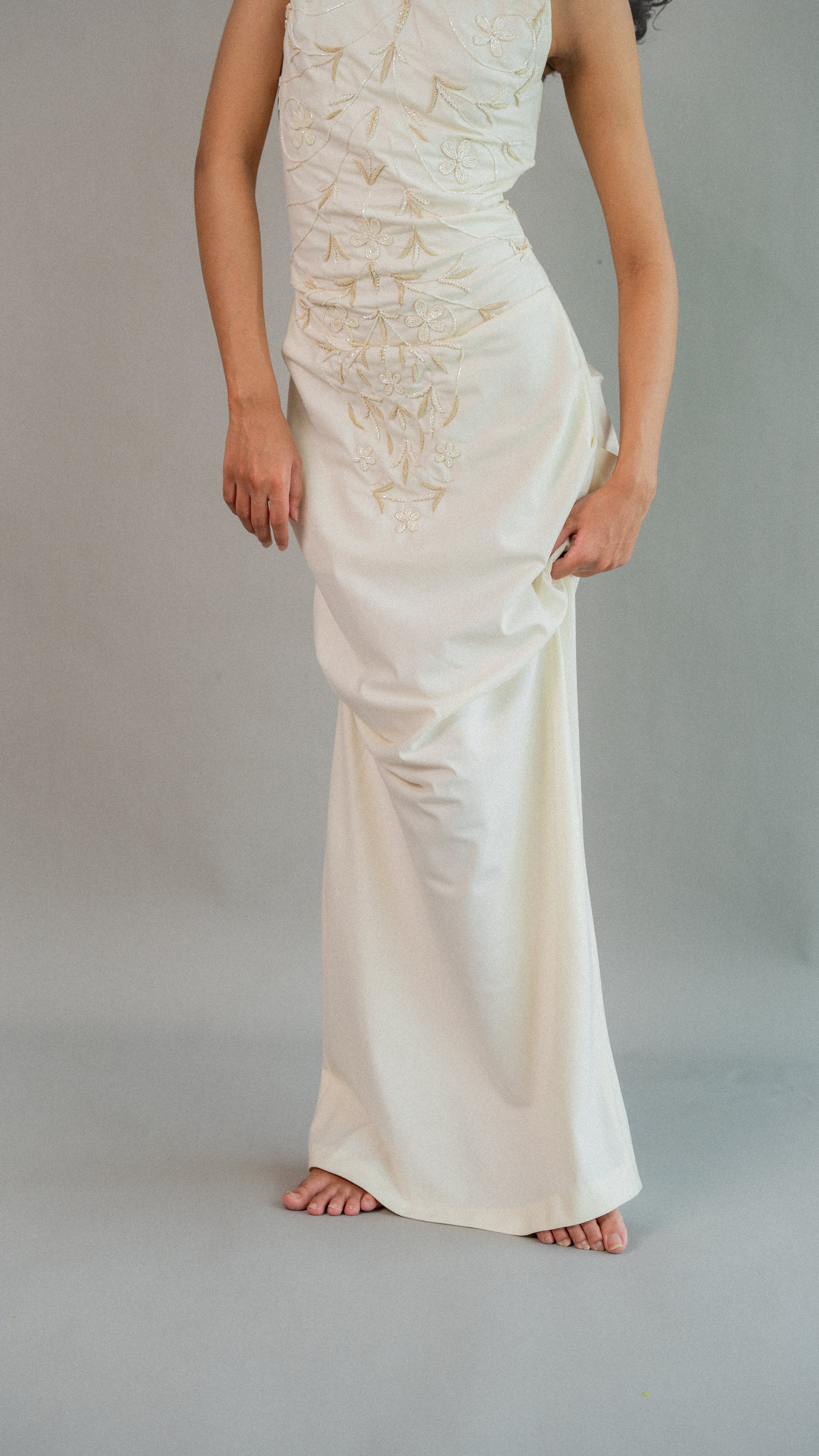 White evening gown with intricate detailing on a plain background