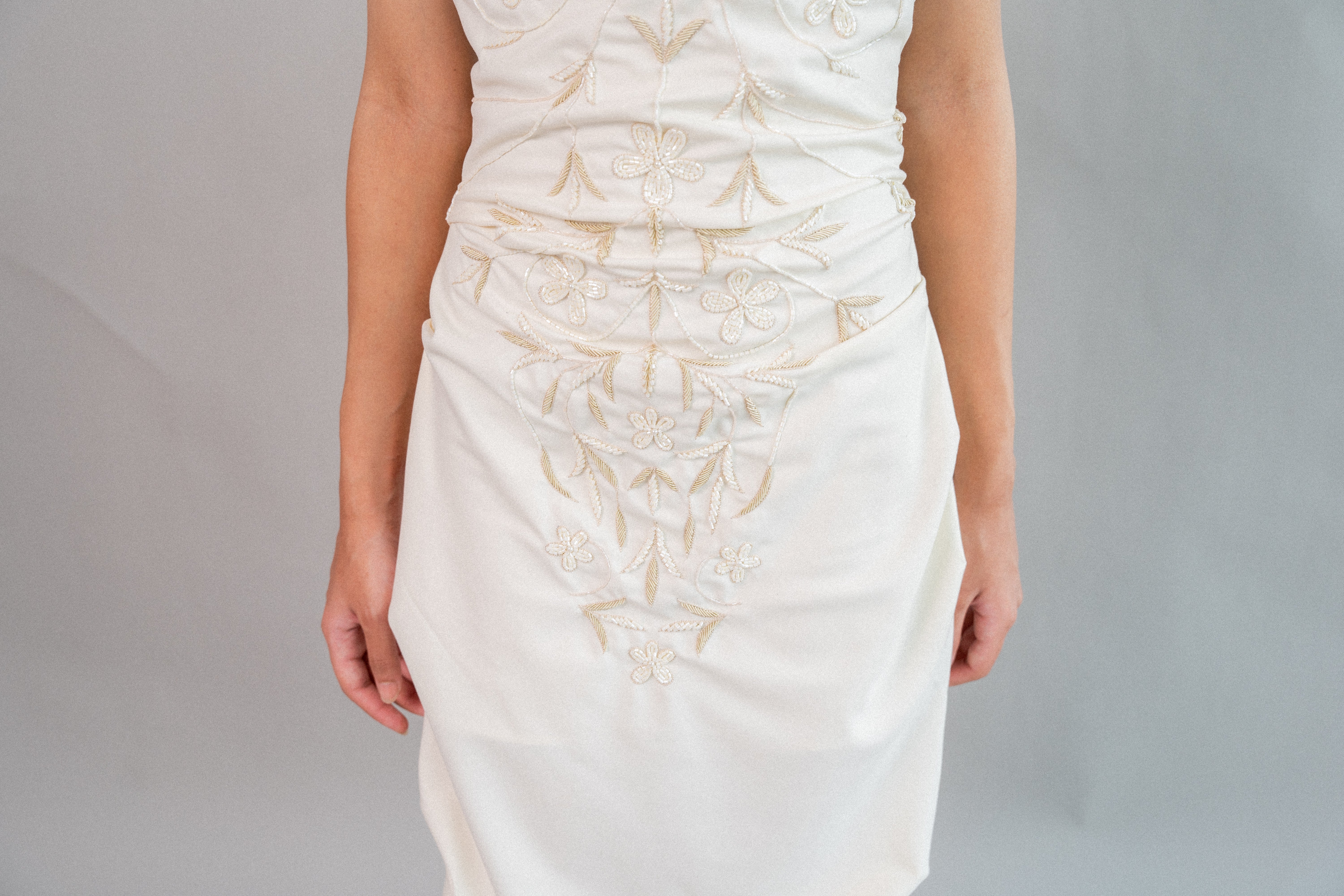 White dress with gold embroidery on a plain background