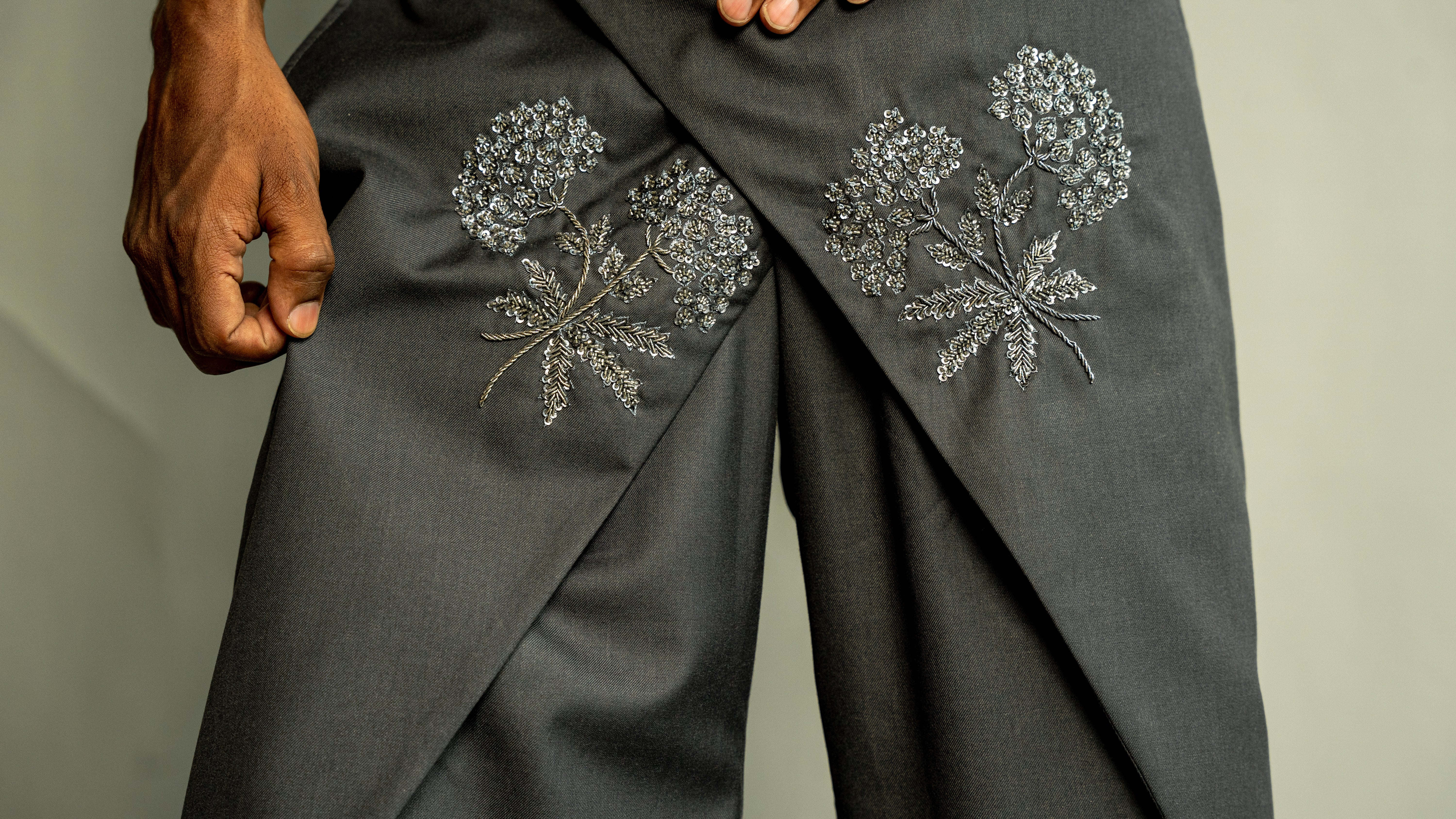 Dark gray pants with floral embroidery on a neutral background
