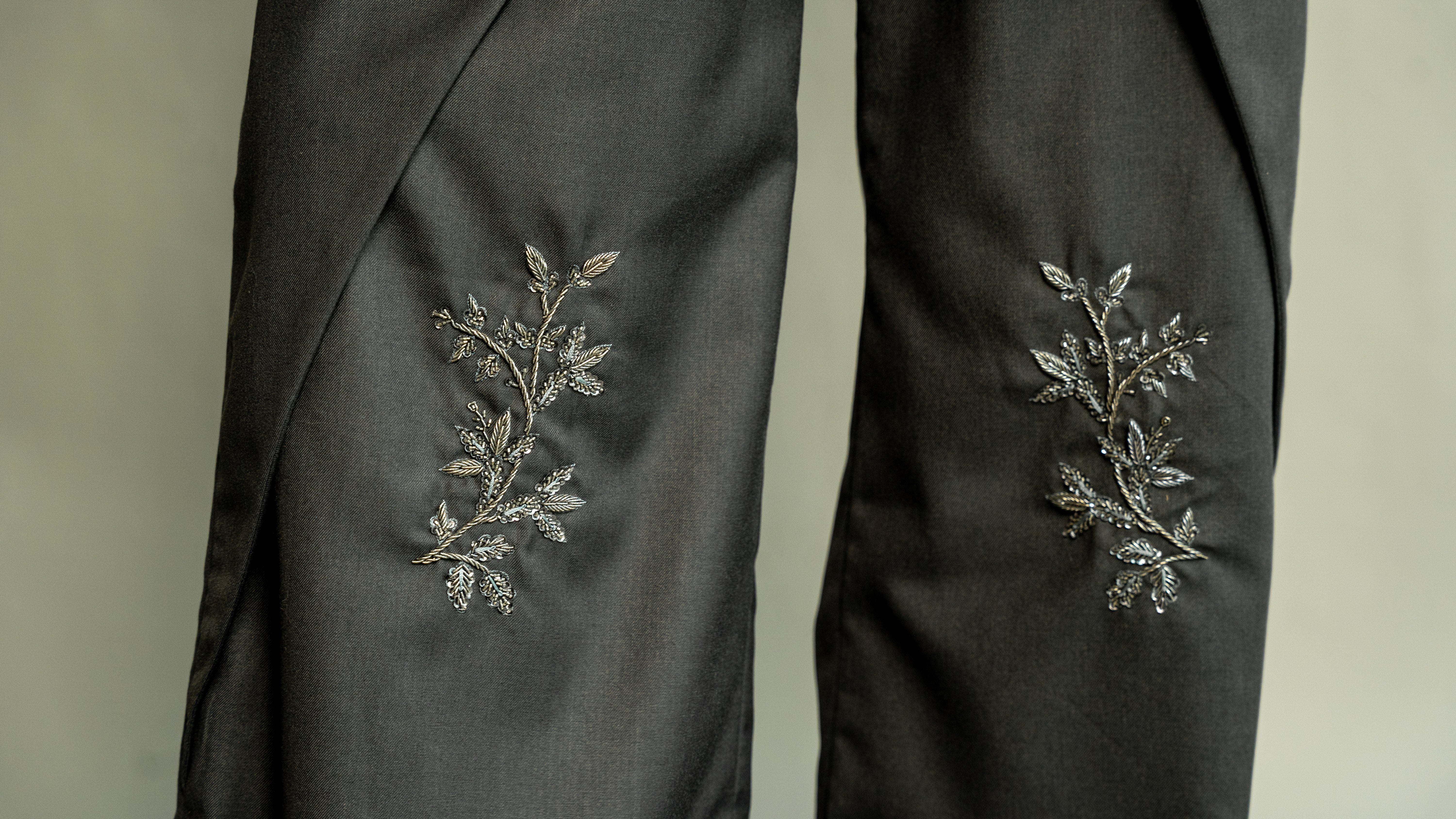 Black garment with floral embroidery on a neutral background