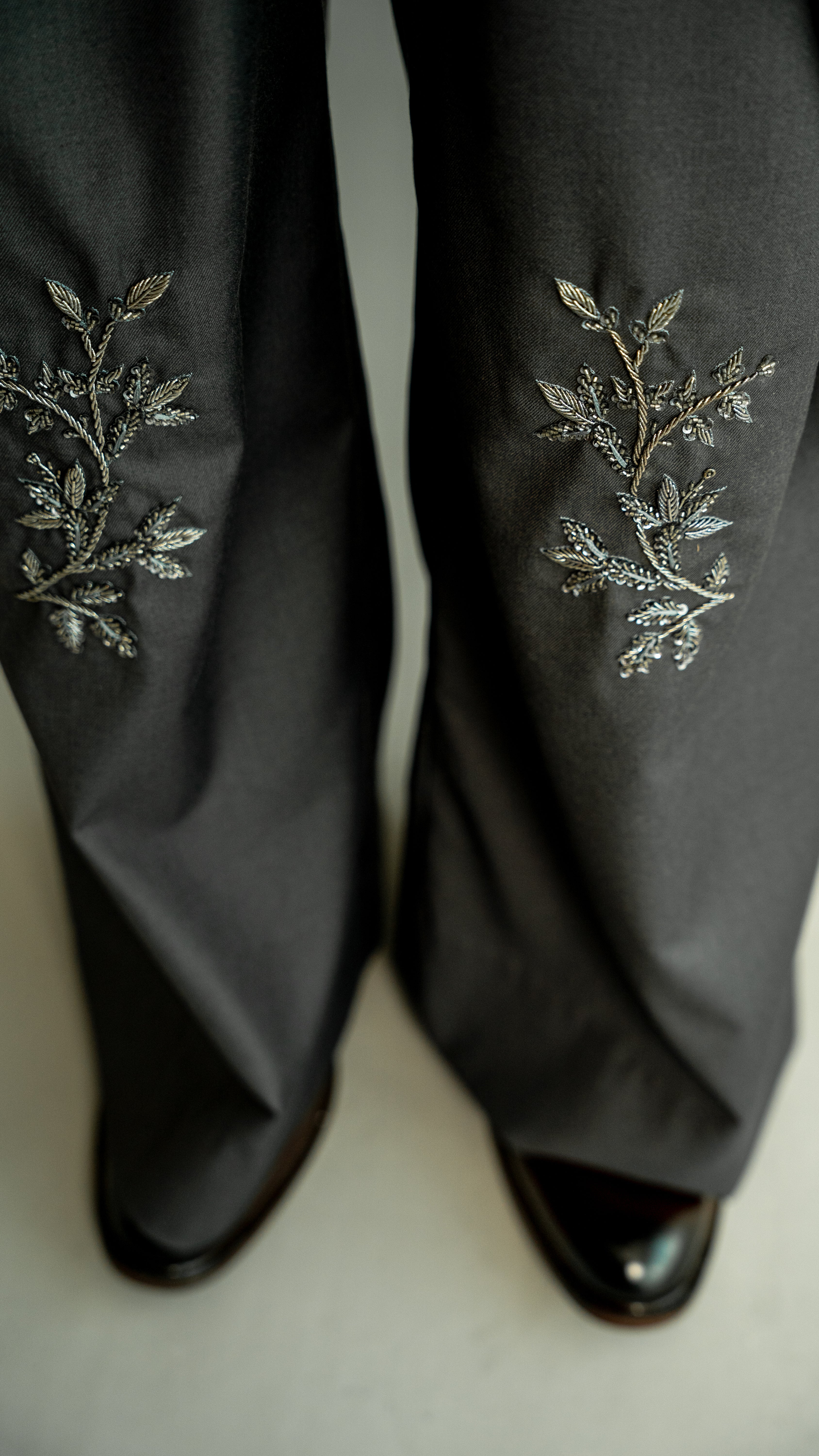 Dark gray pants with floral embroidery on a white background