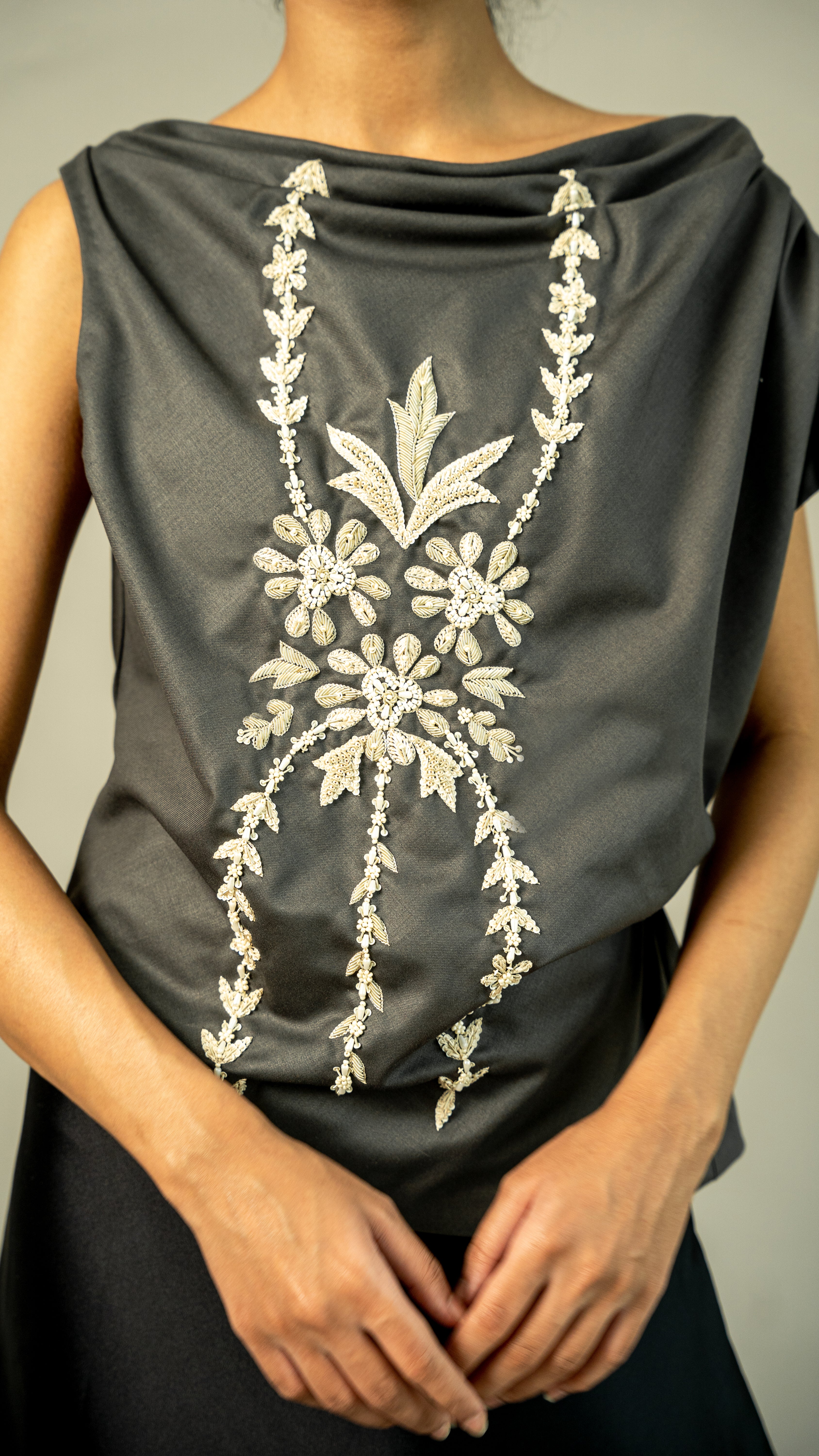 Dark gray top with white floral embroidery on a neutral background