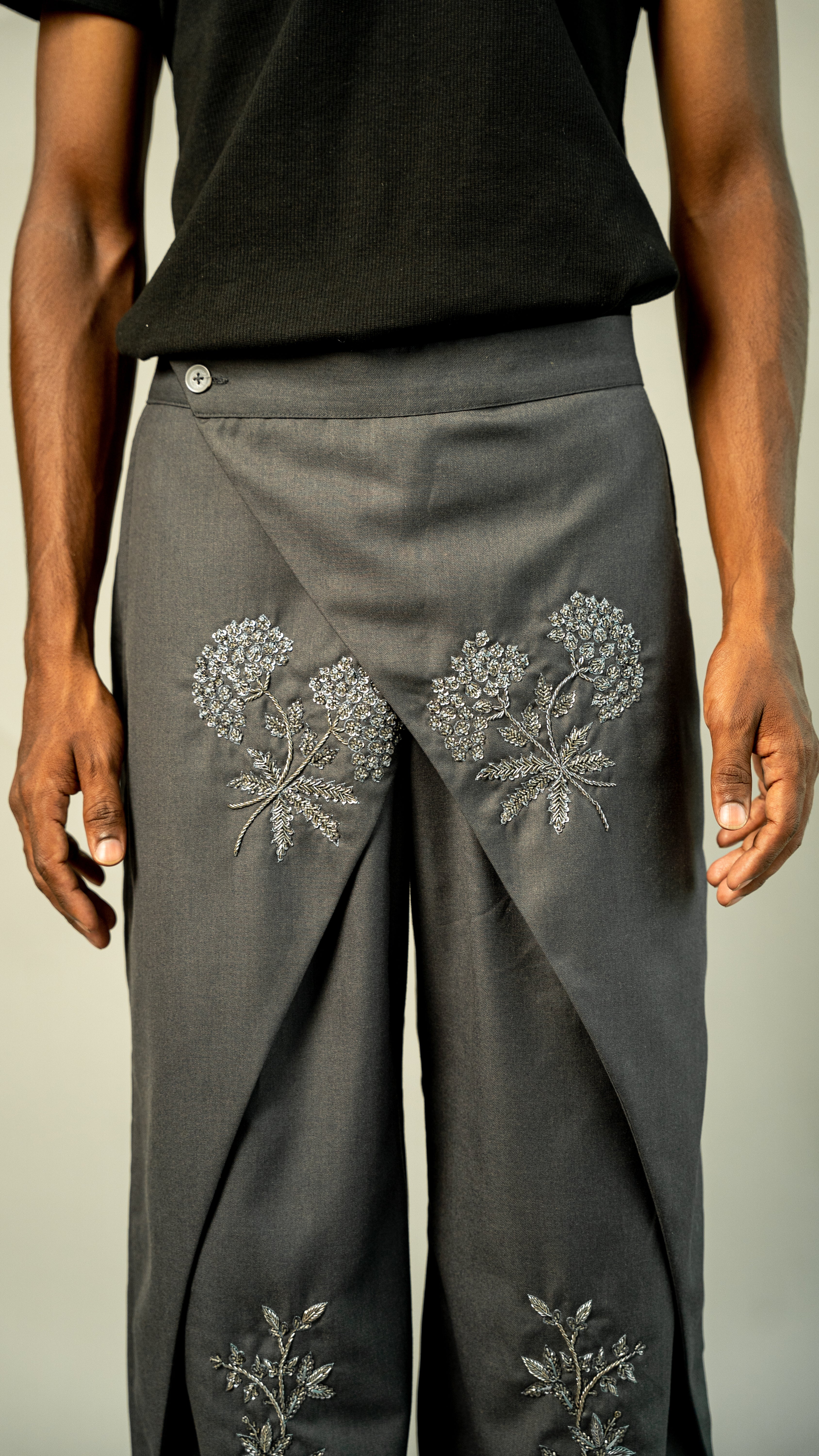Gray pants with floral embroidery on a neutral background